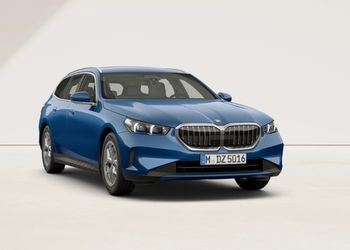 Blauer BMW 5er Touring in Front-Seitenansicht vor hellem Hintergrund.“