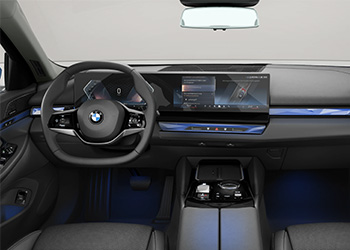 „Innenraum eines BMW 5er Touring mit schwarzen Vordersitzen, Lenkrad, digitalen Displays und Mittelkonsole.