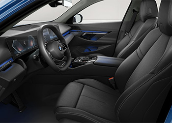 Innenraum eines BMW 5er Touring mit schwarzen Vordersitzen, Lenkrad, digitalen Displays und Mittelkonsole.
